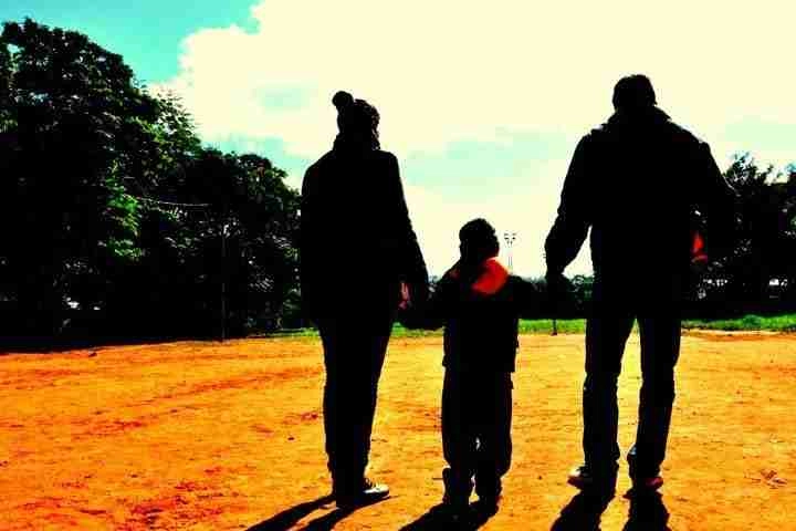 Parents and a young child walking in the sunshine on a grassy field