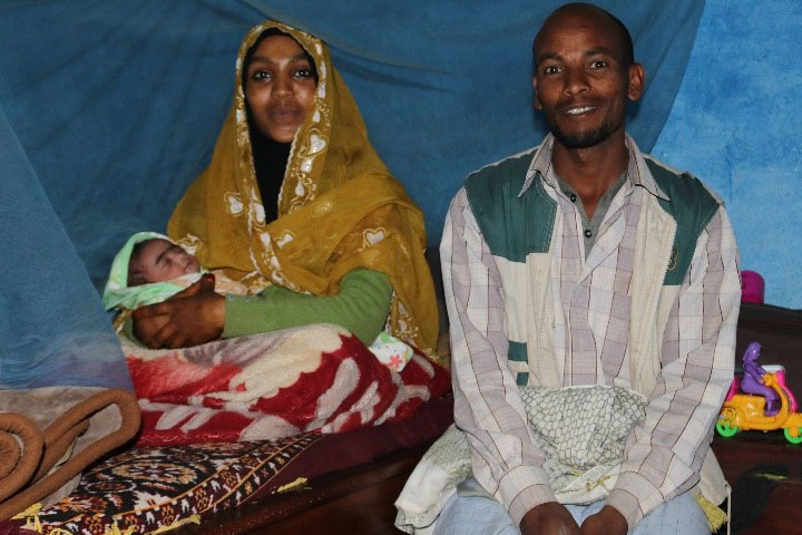 Hussein and his wife holding their baby